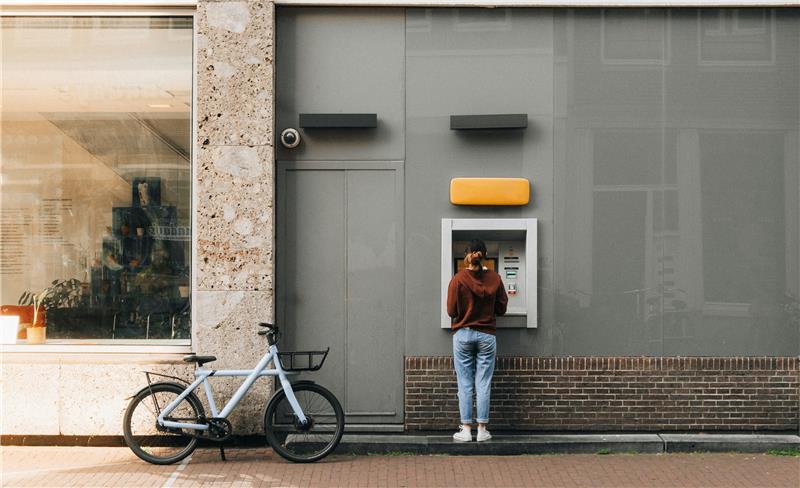 eine Frau hebt Geld an einem Automaten ab