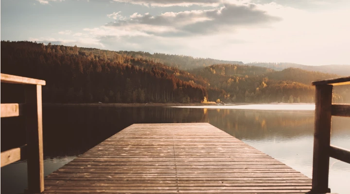 Steg führt auf einen See umringt von Bergen