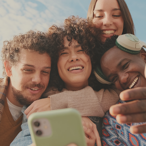 4 Freunde schauen glücklick auf ein Smartphone